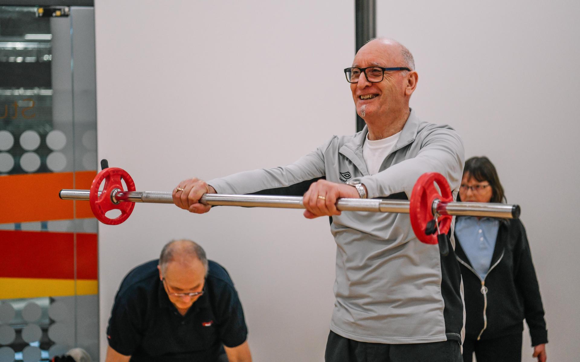 Man smiling and holding a bar weight