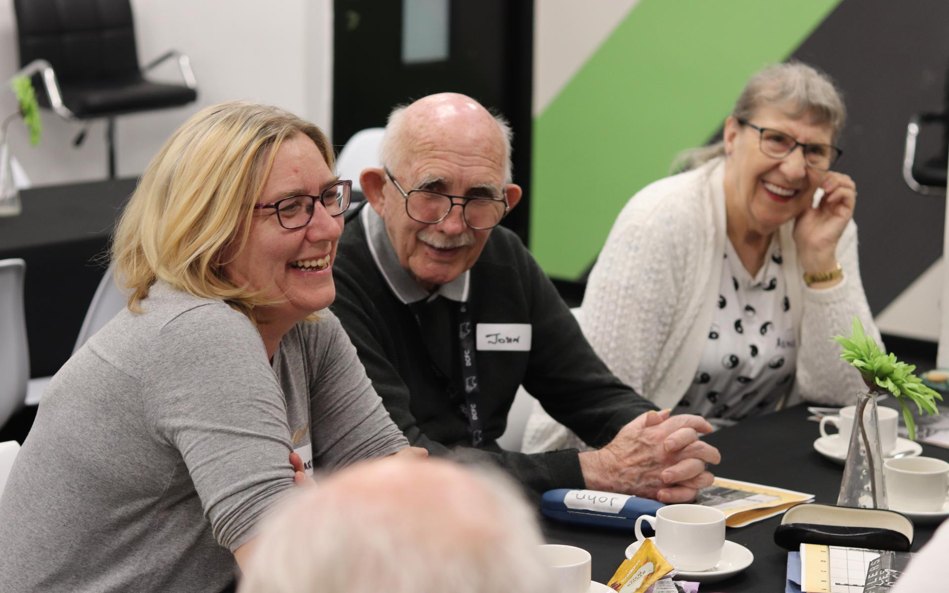 Three people sitting at a table and laughing.