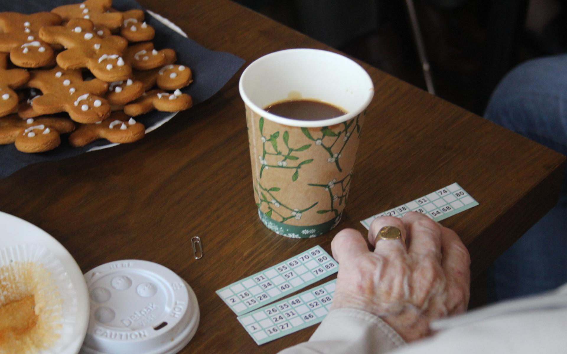 Coffee cup, bingo card and elderly hand.