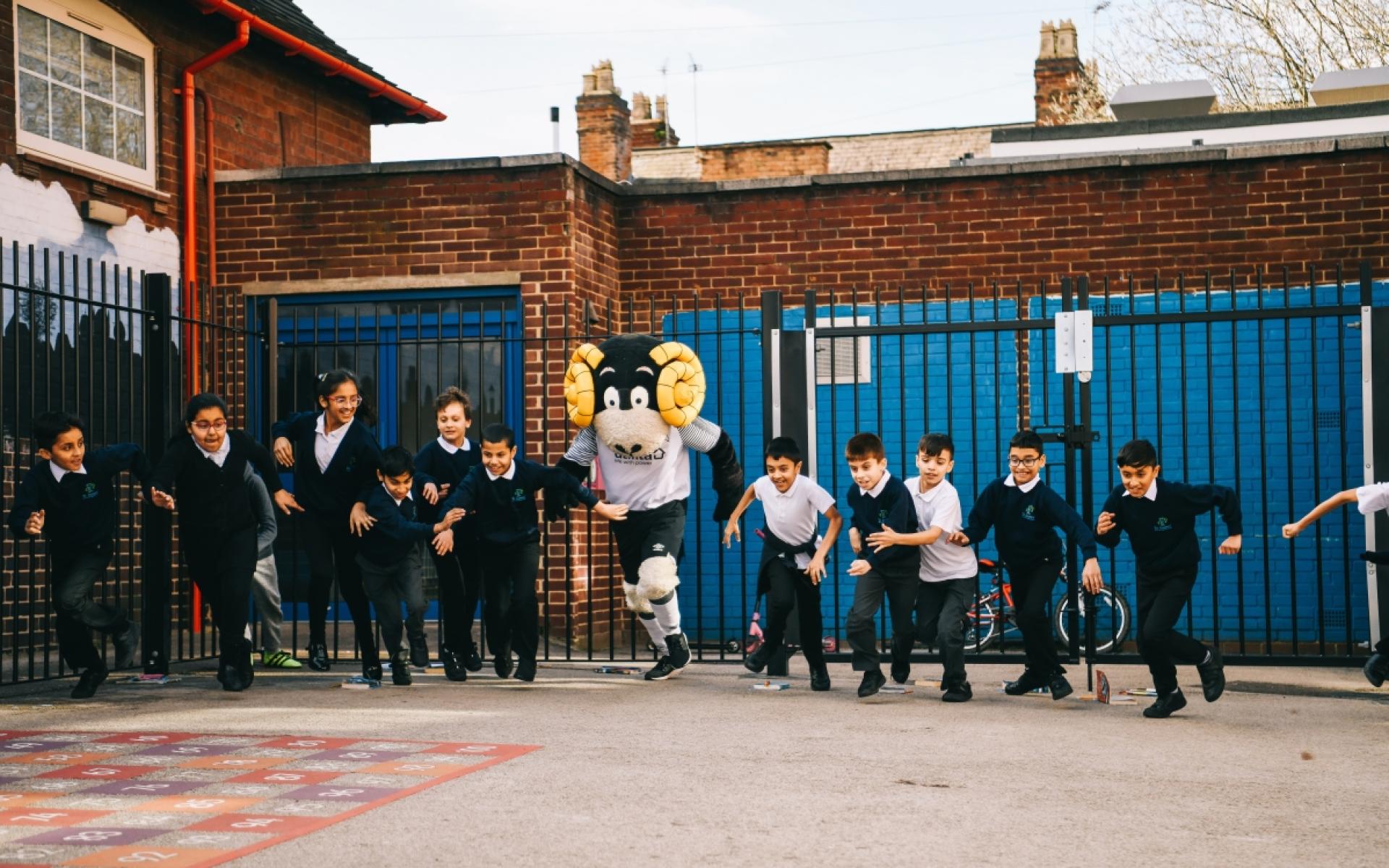 Rammie running with group of primary school children in school playground.