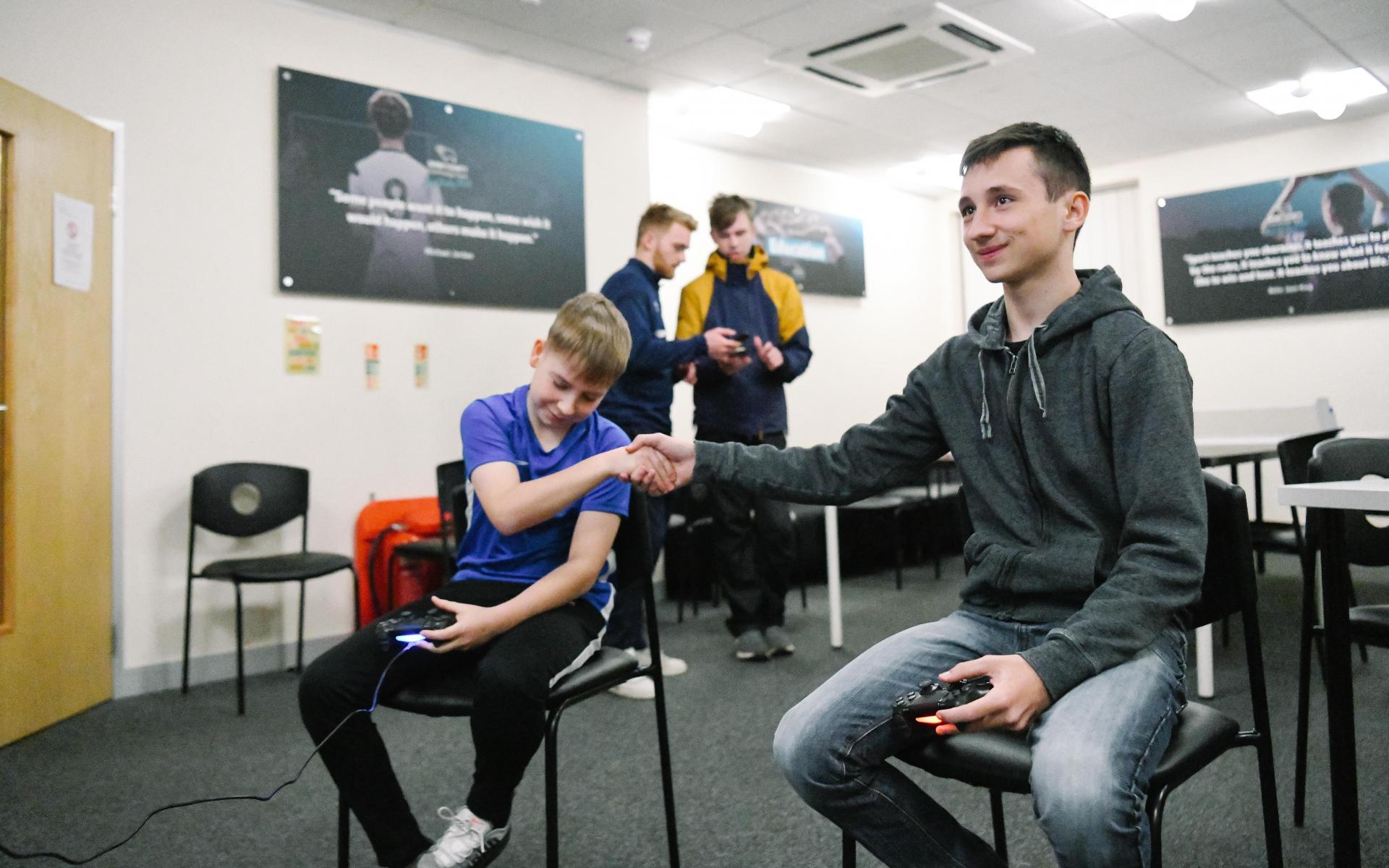 Two young males shaking hands after a video game tournament.