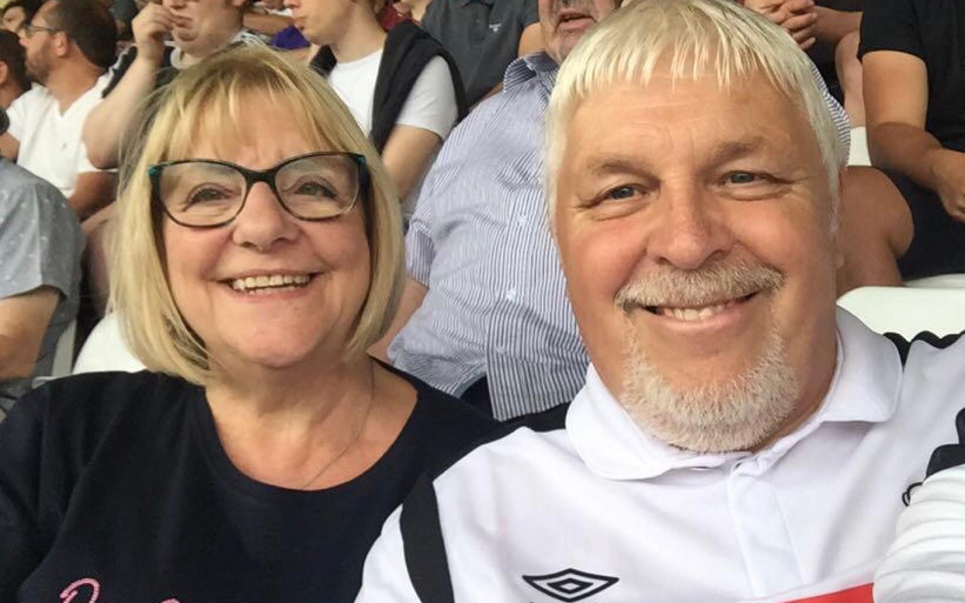Man and woman smiling at football match.