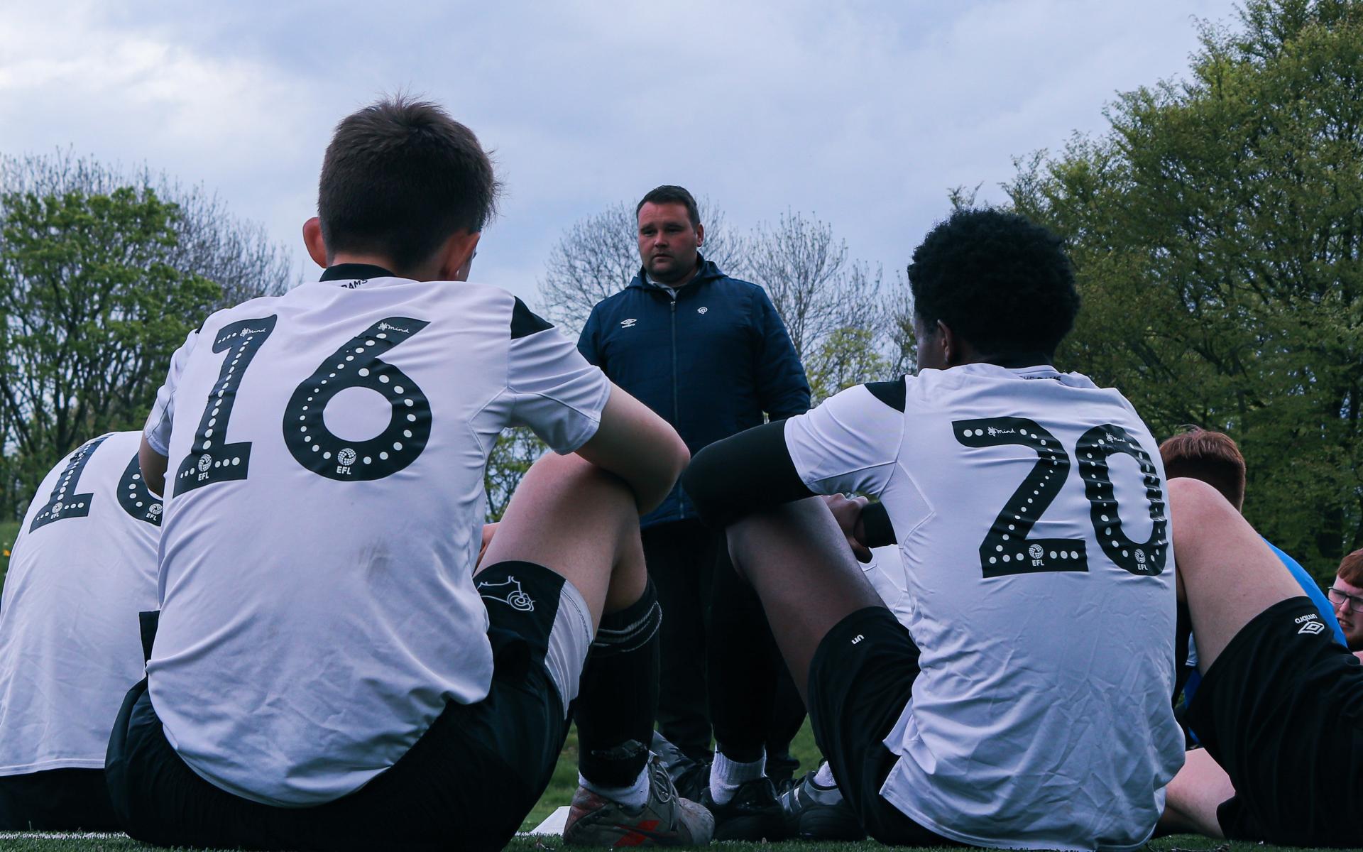 Participants take instructions from a coach during match day