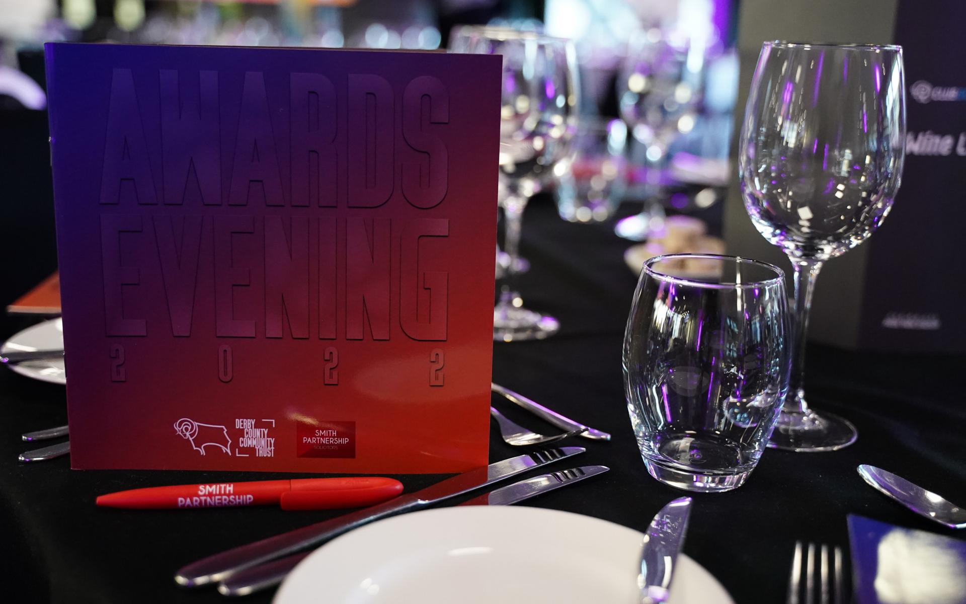 Awards Evening Programme On The Table Next To A Glass And A Pen Sponsored By Smith Partnership