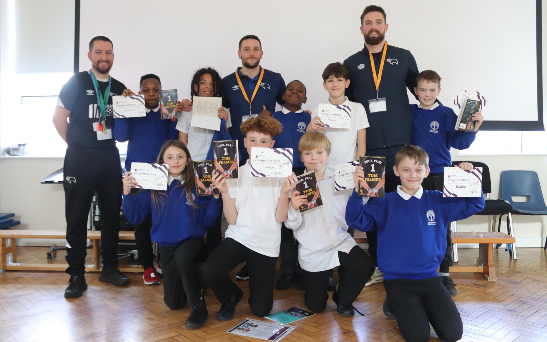 Students pose with certificates and Derby County players.