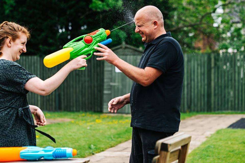 Young woman squirting water gun at male carer