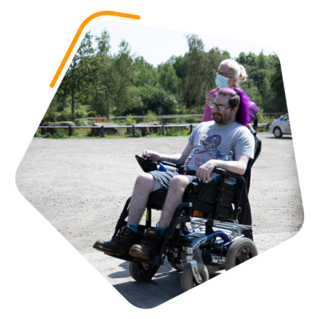 Male in wheelchair walking round a lake
