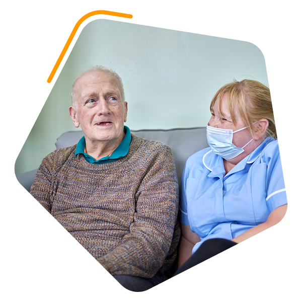 Man sat with female care worker on sofa