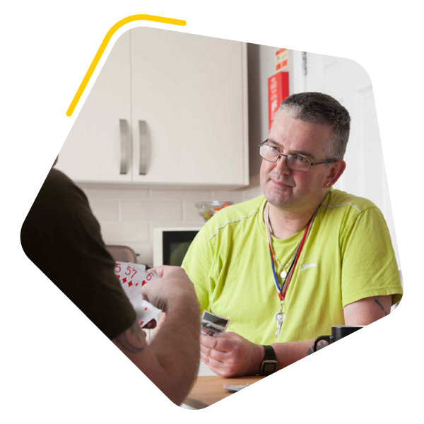 Male service user playing cards with care worker