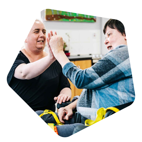 Female care worker holding hands with female service user