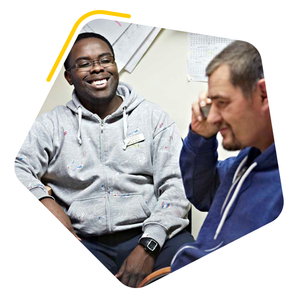 Male care worker sat with male service user