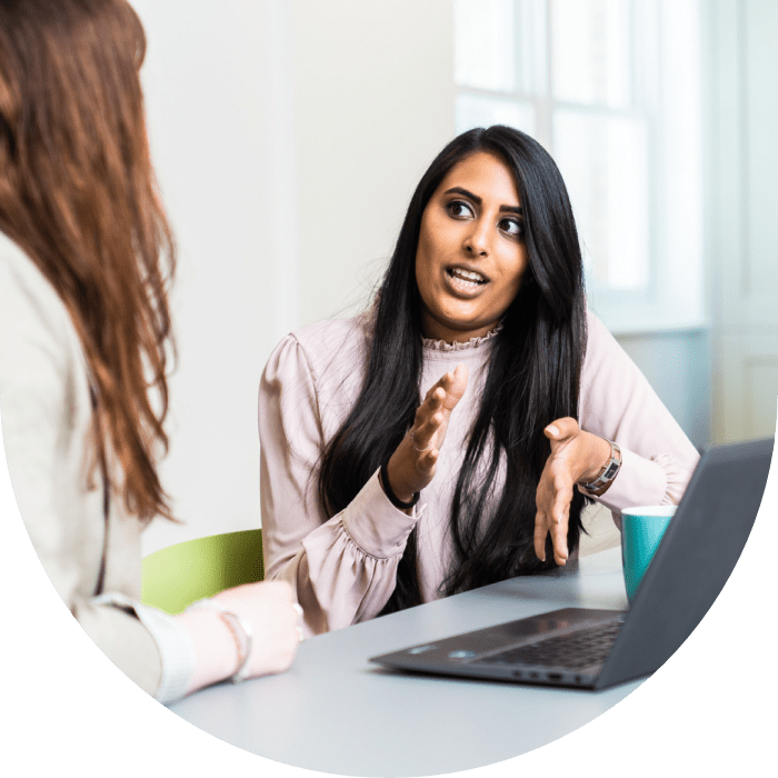  A woman on a laptop talking to a colleague