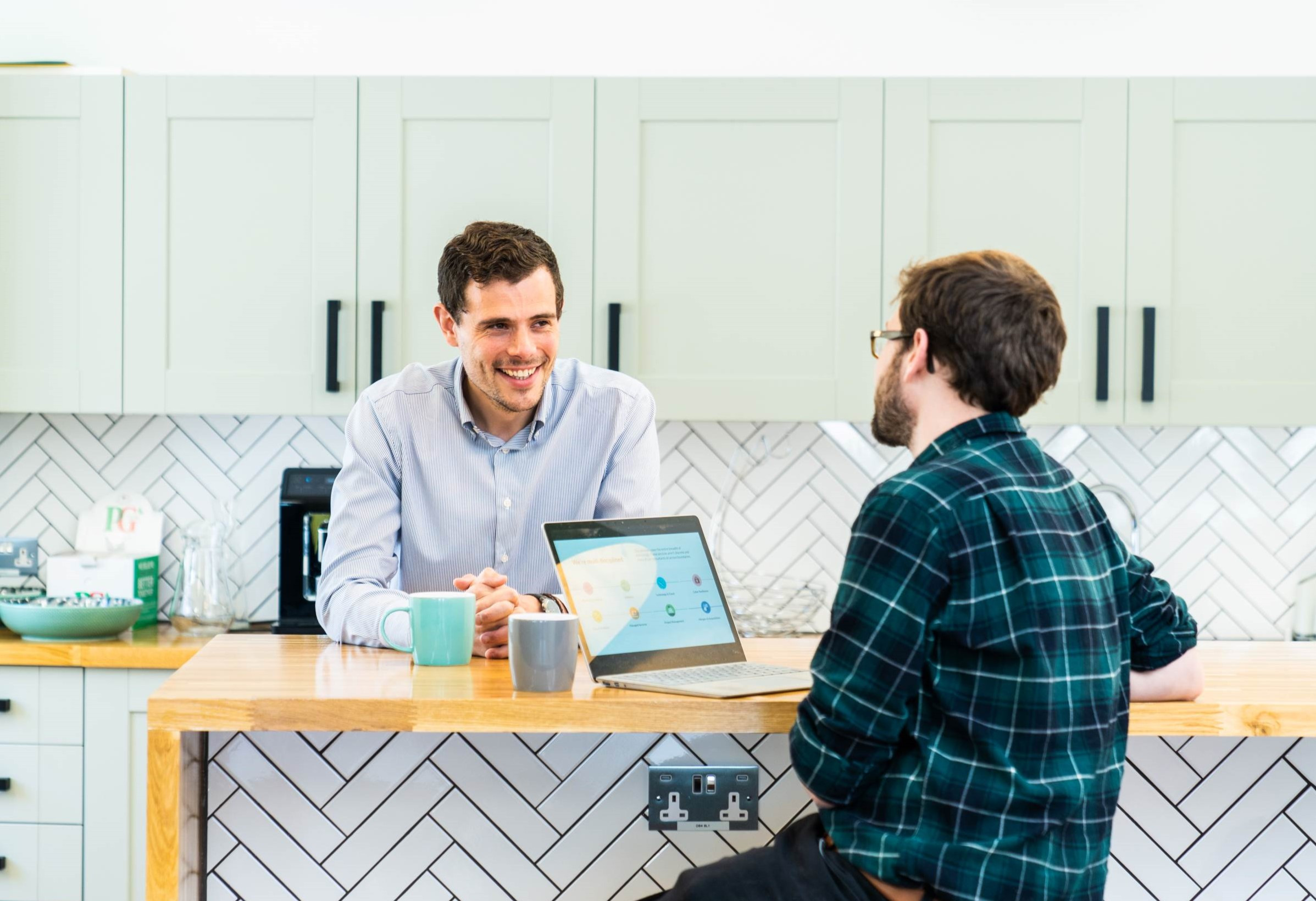 two male colleagues in conversation in a work kitchen