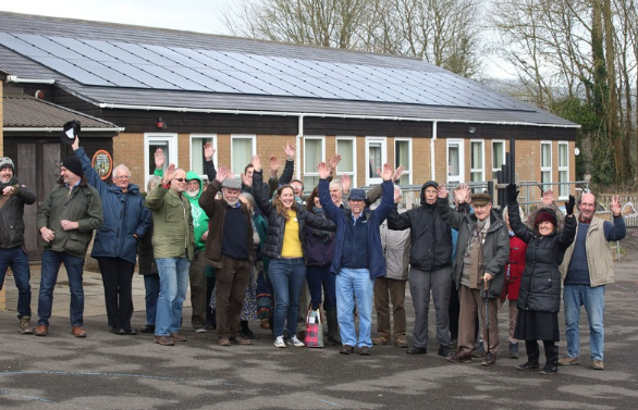 Members of Dorset Community Energy celebrating in front of their solar installation.