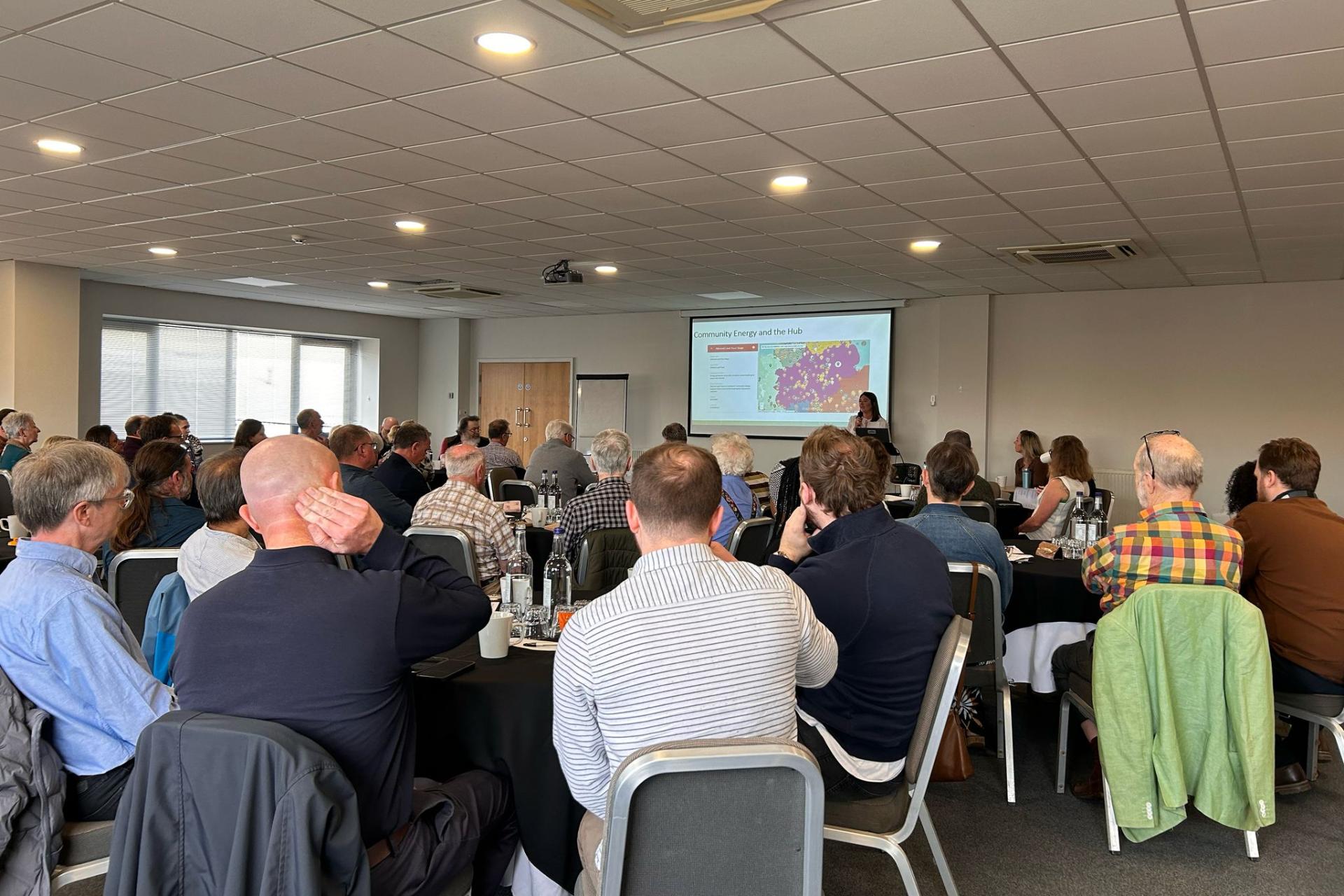 Attendees engaged in a community energy seminar at a recent conference, discussing renewable energy and local initiatives.
