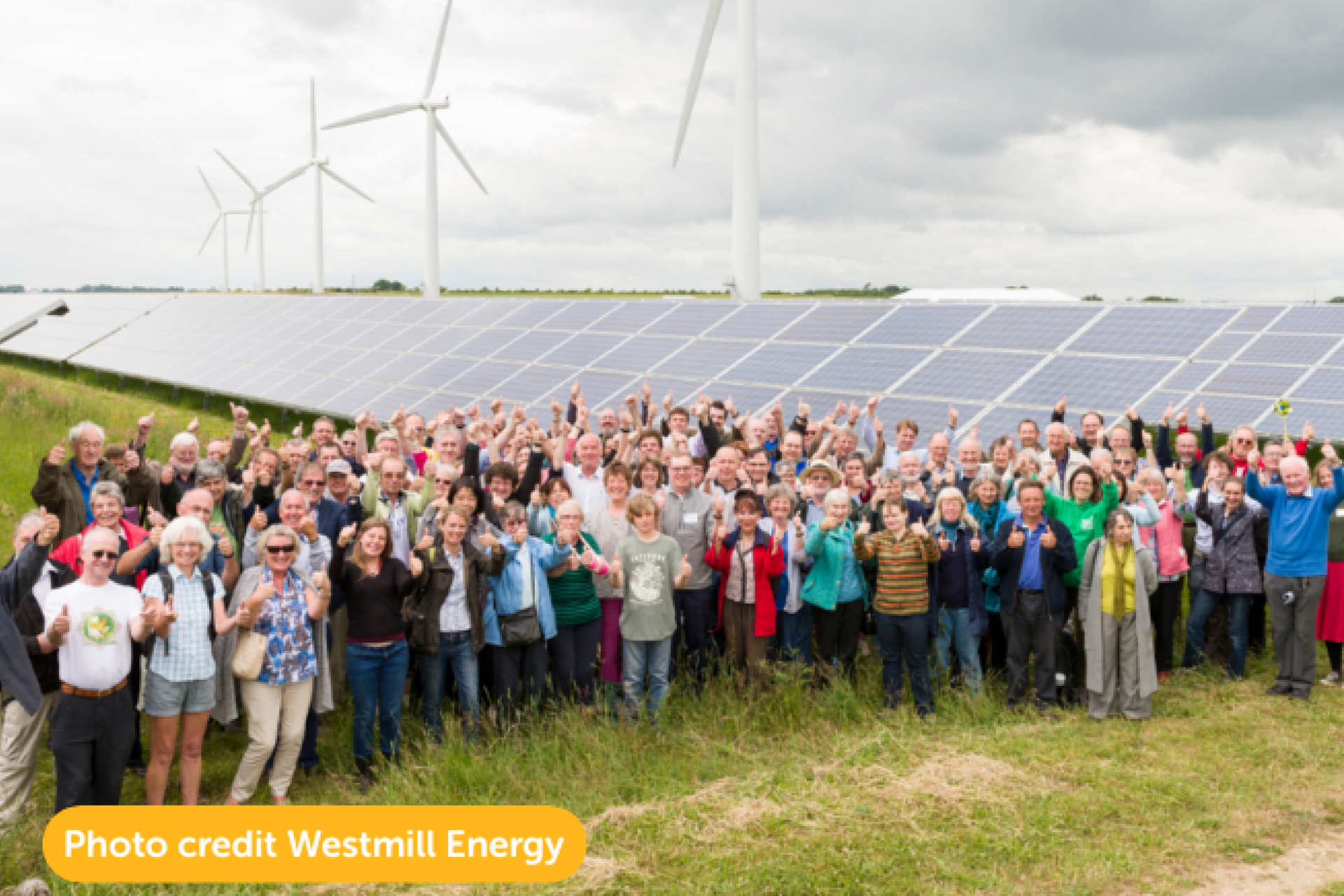 Westmill Energy Co-op members in front of their solar panels and wind turbines.