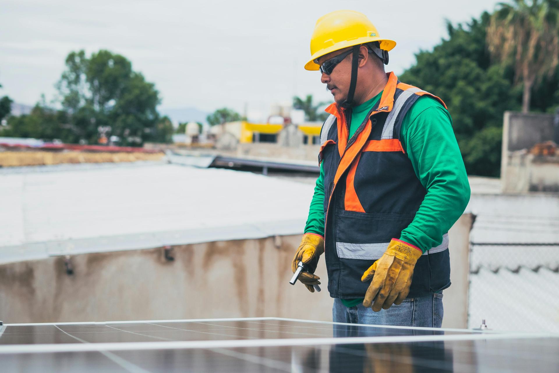 Engineer securely fitting solar panels onto a rooftop under clear skies.