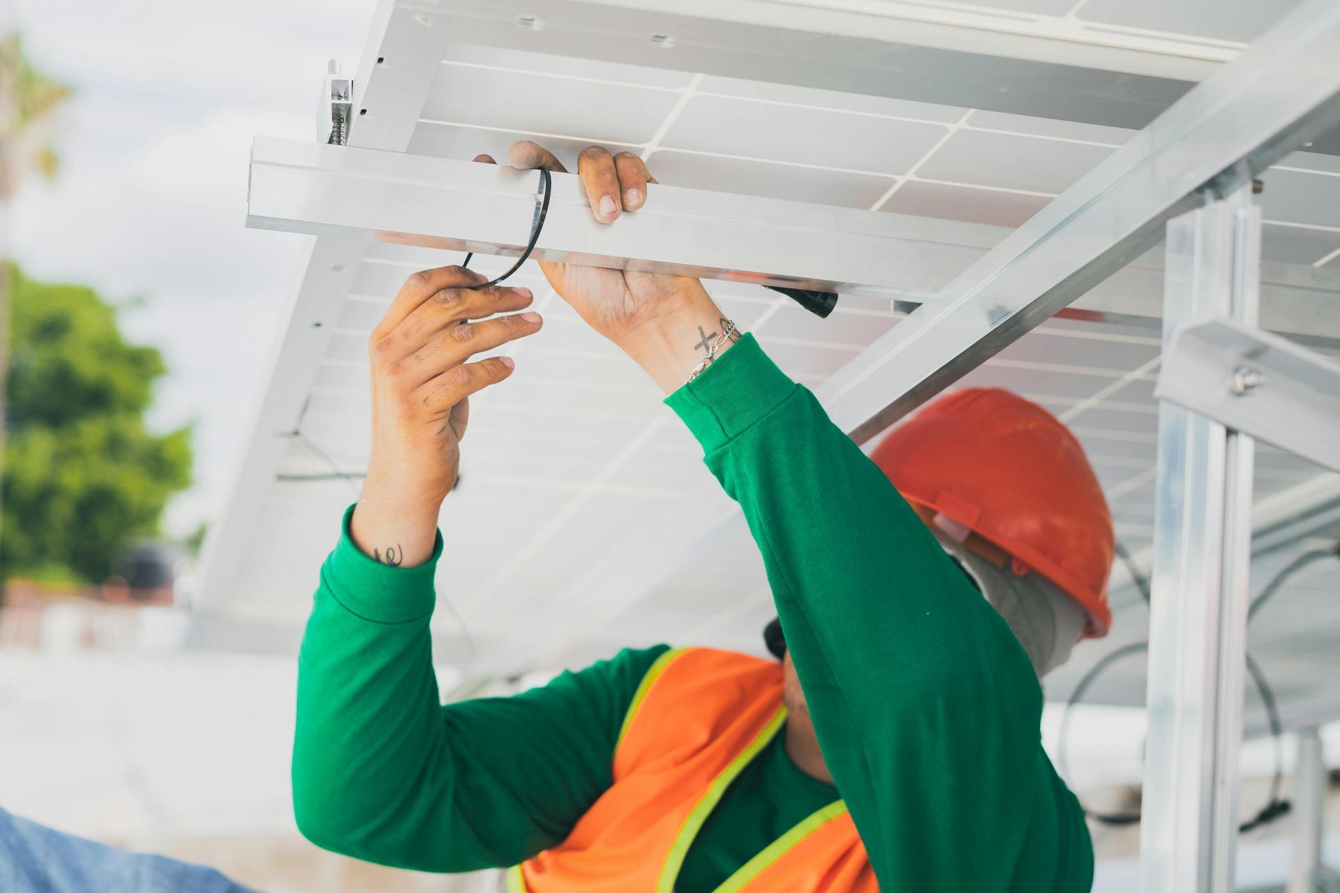 An engineer installing solar panels on a rooftop, contributing to renewable energy generation.