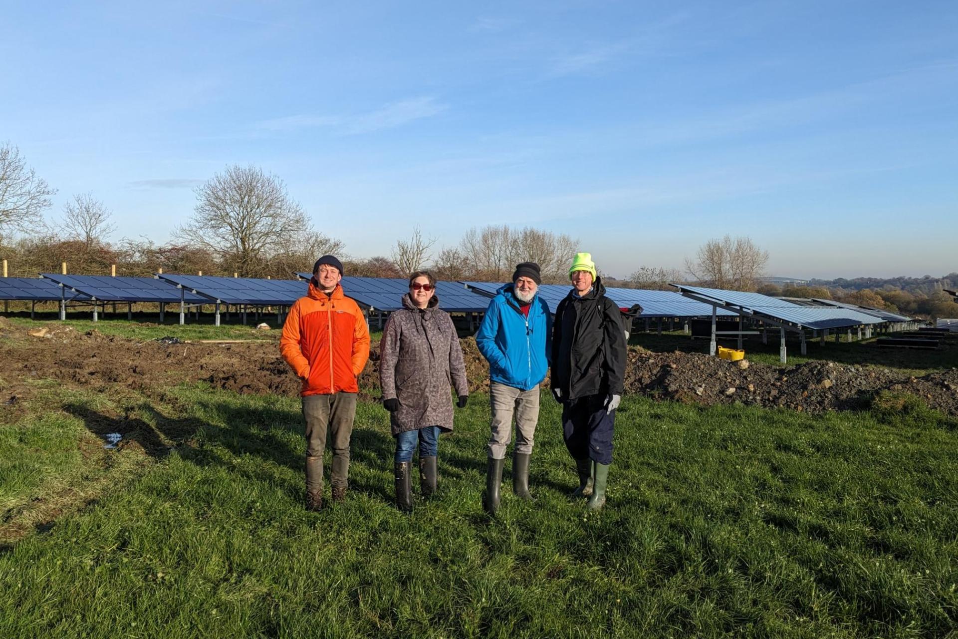 The Big Solar Co-op team standing in front of recycled solar panels.