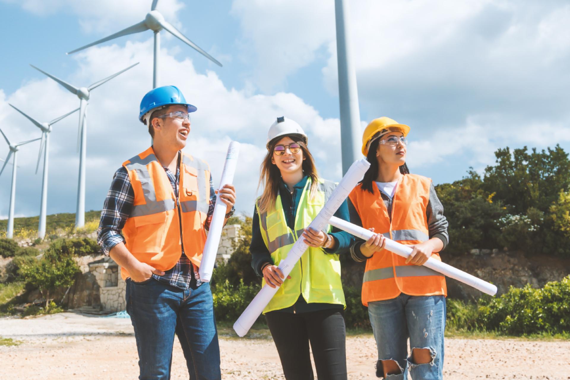Engineers review plans in front of wind turbines.